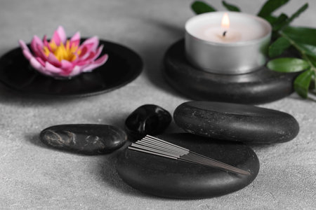 Stones with acupuncture needles on gray textured tableの写真素材