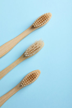 Bamboo toothbrushes on light blue background, flat layの写真素材