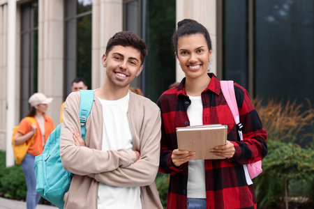 Portrait of happy young students with backpacks outdoors