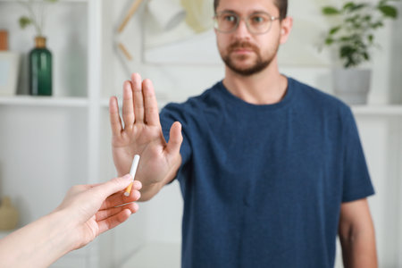 Man refusing cigarette indoors, selective focus. Quitting smoking conceptの写真素材