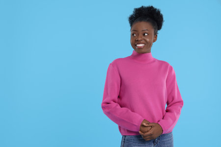 Portrait of happy young woman on light blue background. Space for textの写真素材