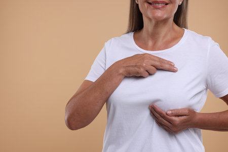 Woman doing breast self-examination on light brown background, closeup. Space for textの写真素材