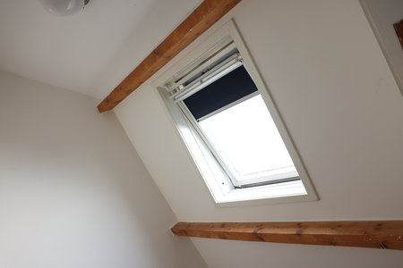 Roof window on slanted ceiling indoors, low angle view
