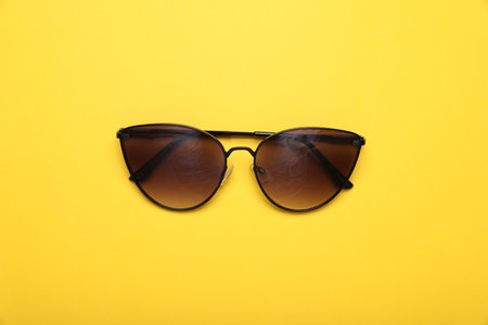 Stylish sunglasses on yellow background, top viewの写真素材