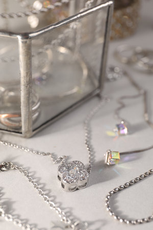 Different metal chains and stylish earrings on light table, closeup. Luxury jewelryの写真素材