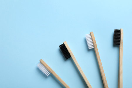 Bamboo toothbrushes on light blue background, flat lay. Space for textの写真素材