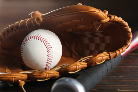Baseball glove, bat and ball on wooden table, closeupの写真素材