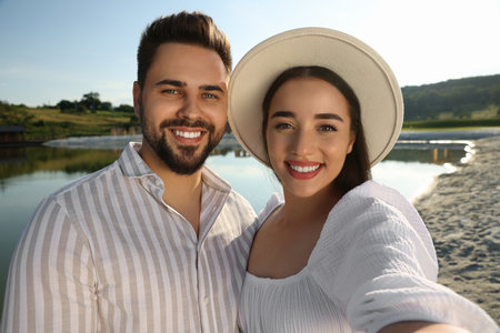 Romantic date. Beautiful couple making selfie near lake on sunny dayの写真素材