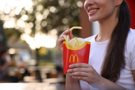 Lviv, Ukraine - September 26, 2023: Woman with McDonald's French fries outdoors, closeup. Space for...
