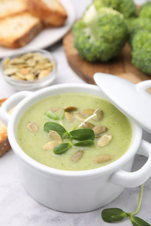 Delicious broccoli cream soup with pumpkin seeds on white marble table, closeup. Space for textの写真素材