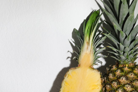 Whole and cut ripe pineapples on white background, closeup. Space for textの写真素材