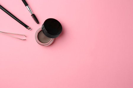 Eyebrow pomade with henna effect and professional tools on pink background, flat lay. Space for textの写真素材