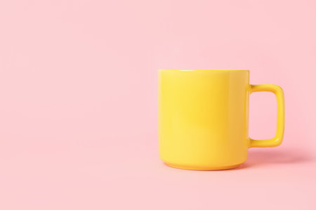 One yellow ceramic mug on pink background, space for textの写真素材