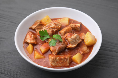 Delicious goulash in bowl on black wooden table, closeupの写真素材