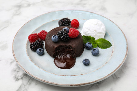 Delicious chocolate fondant served with fresh berries and ice cream on white marble table, closeupの写真素材