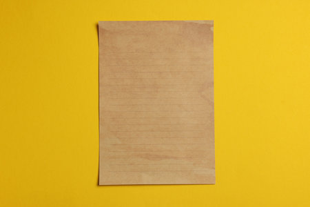 Sheet of old parchment paper on yellow background, top viewの写真素材