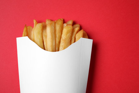 Paper cup with French fries on red table, top view. Space for textの写真素材