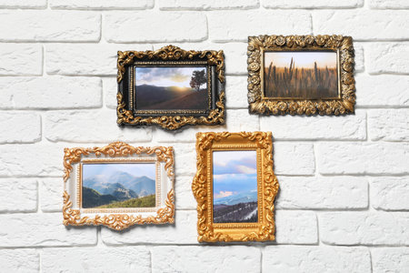 Vintage frames with photos of beautiful landscapes hanging on white brick wallの写真素材
