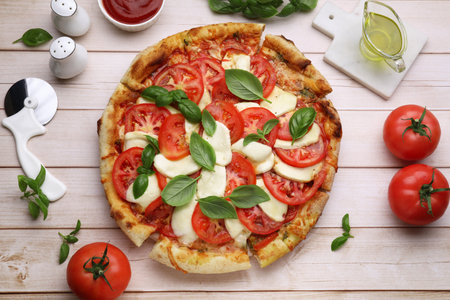 Delicious Caprese pizza with tomatoes, mozzarella and basil on light wooden table, flat layの写真素材