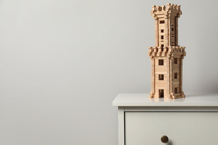 Wooden tower on chest of drawers near light gray wall, space for text. Children's toysの写真素材