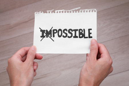 Motivation concept. Woman holding paper with changed word from Impossible into Possible by crossing over letters I and M indoors, closeupの写真素材