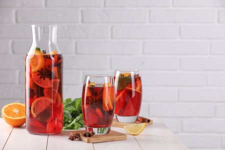 Delicious punch drink, slices of fruits and anise stars on white wooden table. Space for textの写真素材