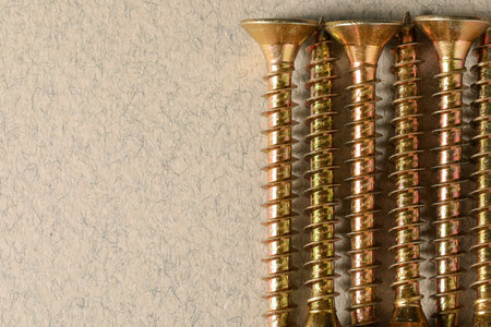 Many metal screws on beige background, flat lay. Space for text
