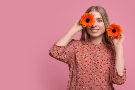 Beautiful woman with spring flowers in hands on pink background, space for textの写真素材