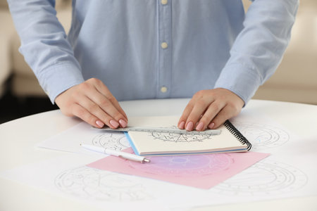 Astrologer using zodiac wheel for fate forecast at table, closeup. Fortune telling