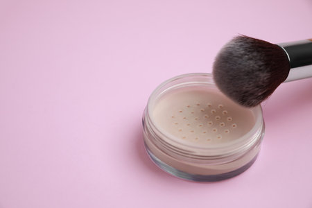 Loose face powder and brush on pink background, space for textの写真素材