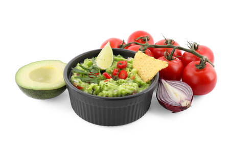 Delicious guacamole with nachos chips, lime and different ingredients isolated on whiteの写真素材