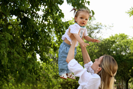 Mother with her daughter spending time together in park. Space for text