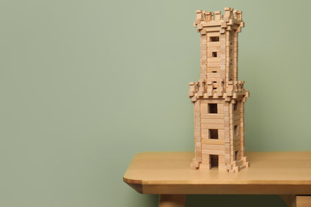 Wooden tower on table near olive wall, space for text. Children's toysの写真素材