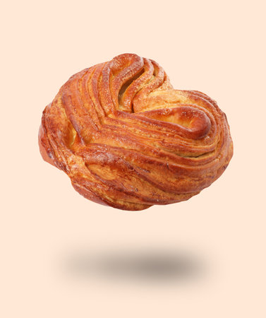 Freshly baked bun in air on pastel pink background