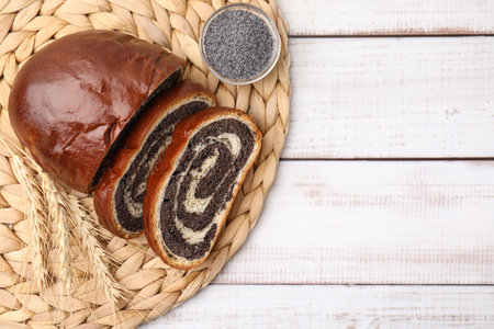 Cut poppy seed roll and spikelets on white wooden table, top view with space for text. Tasty cakeの写真素材