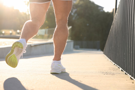 Man running outdoors on sunny day, closeup. Space for text