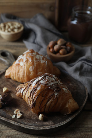 Delicious croissants with chocolate and nuts on wooden tableの写真素材