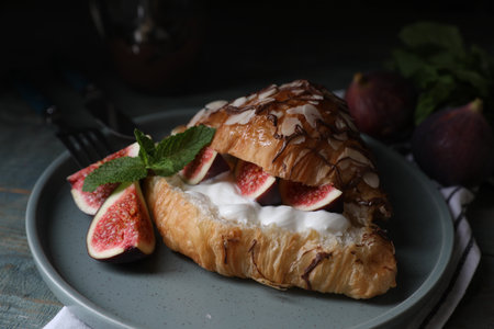 Delicious croissant with figs and cream on light blue wooden table, closeupの写真素材