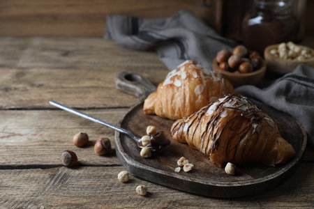 Delicious croissants with chocolate and nuts on wooden table, space for textの写真素材