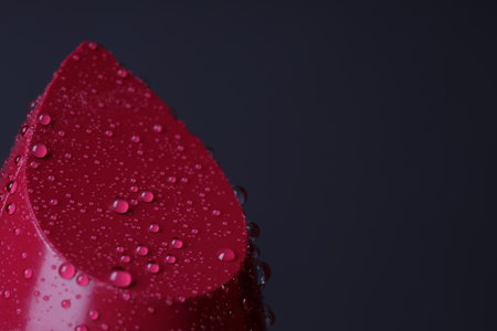 Red lipstick with water drops on dark gray background, macro view. Space for textの写真素材