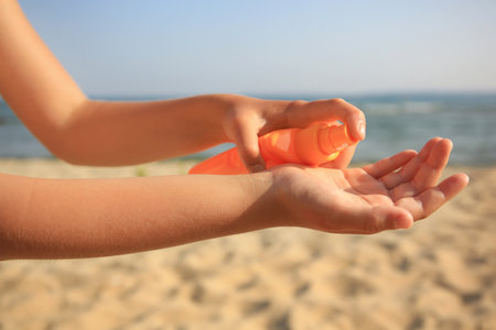 Child applying sunscreen near sea, closeup. Sun protection careの写真素材