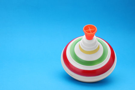 One bright spinning top on light blue background, space for text. Toy whirligigの写真素材