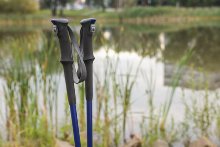 Two Nordic walking poles near lake outdoors, closeup. Space for textの写真素材
