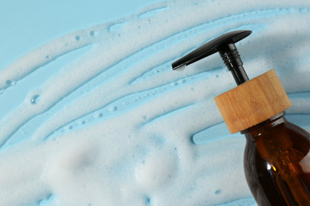 Bottle with cleansing foam on light blue background, top view. Cosmetic productの写真素材