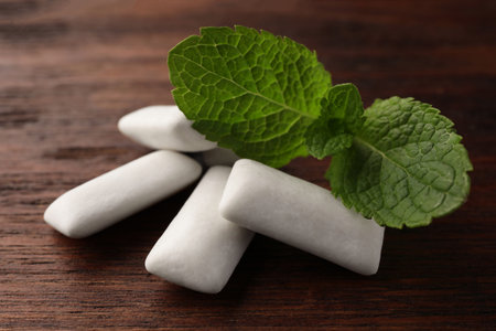 Tasty white chewing gums and mint leaves on wooden table, closeupの写真素材