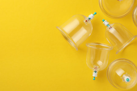 Plastic cups on yellow background, flat lay with space for text. Cupping therapyの写真素材
