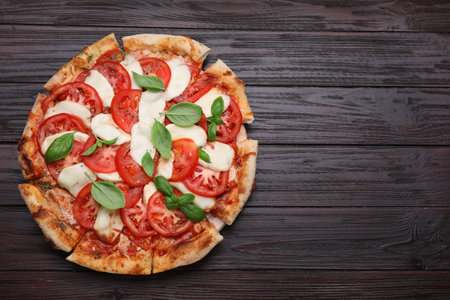 Delicious Caprese pizza with tomatoes, mozzarella and basil on dark wooden table, top view. Space for textの写真素材