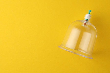 Plastic cup on yellow background, top view with space for text. Cupping therapyの写真素材