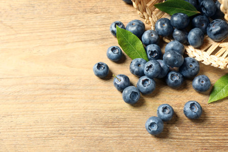 Fresh tasty blueberries with leaves on wooden table, space for textの写真素材