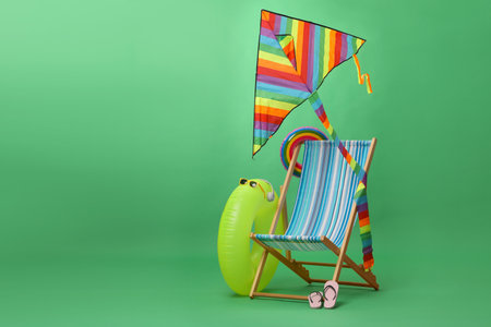 Deck chair, kite and beach accessories on green background, space for text. Summer vacationの写真素材